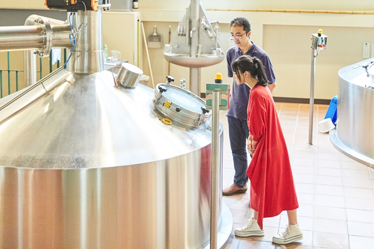 「タンクの中では麦汁を煮沸中です」。スタッフ神田さんの説明を熱心に聞く永尾さん。